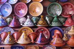 Painted tagine pots and plates stacked in a pottery shop in Morocco