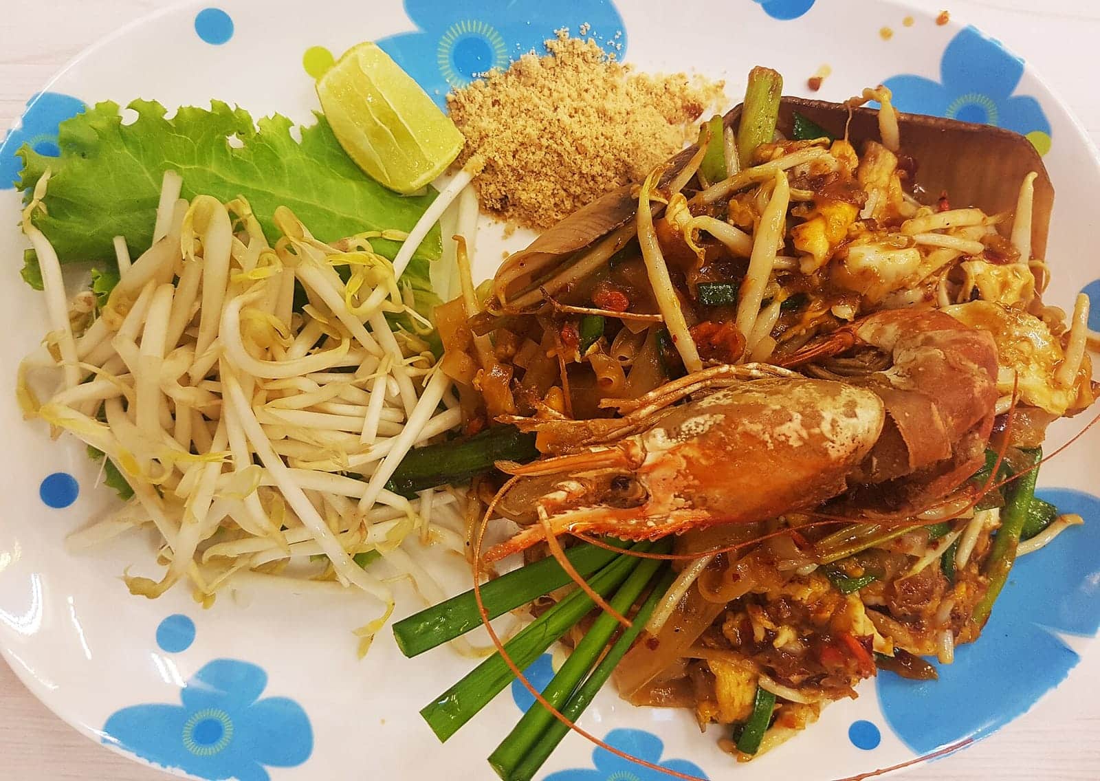 A plate of pad thai with lime and bean sprouts